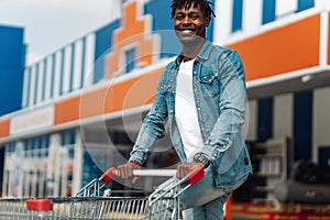 Afro american black man with shopping cart in front of mall shopping mall