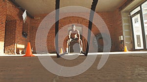 Afro american bodybuilder with battle rope in cross-fit training centre