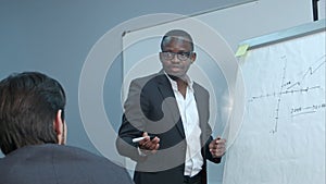 Afro-american businessman making presentation of a business plan on the flipchart