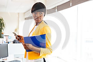 Afro american businesswoman holding folder and smartphone