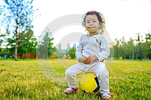 afro american cheerful curly girl playing a yellow ball in sunset park