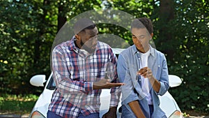 Afro-american dad demanding car key teenage son car background, parent control