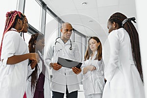 Afro-American doctor leading his team with folded arms and looking at the camera.