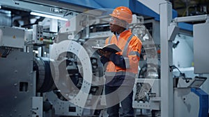 Afro american engineer taking notes of project data at manufacturing factory.