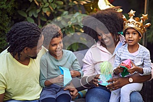 Afro-american family gathered on birthday party, smiling, playing with paper hat and boats
