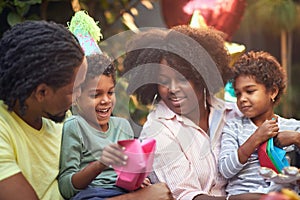 Afro-american family playing together at birthday party with paper hat and boats