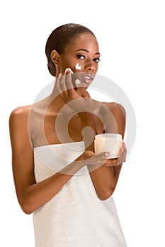 Afro-American girl wrapped in towel putting cream