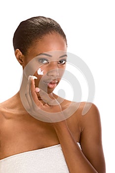 Afro-American girl wrapped in towel putting cream