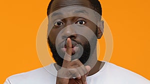 Afro-american guy making silence gesture closeup, asking be quiet, conspiracy