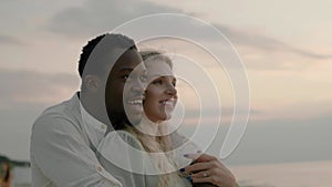 Afro-American husband hugs blonde wife and points to horizon