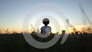 Afro-american lady practicing yoga, sitting in lotus position, sunset in city
