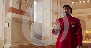 Afro american male gospel singer in 30s. Young man wearing red suit moving hands while singing spiritual music in house