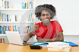 Afro american male student showing thumb up at desk