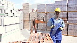 Afro american male worker posing near redbricks at a building materials warehouse