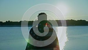 Afro-american man with American flag on shoulders looks into distance at sunrise