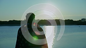 Afro-american man with American flag on shoulders looks into distance at sunrise