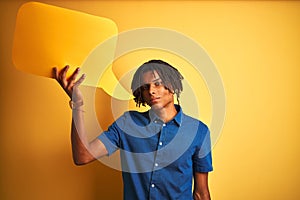 Afro american man with dreadlocks holding speech bubble over isolated yellow background with a confident expression on smart face