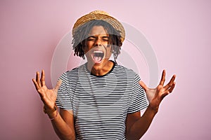 Afro american man with dreadlocks wearing navy t-shirt and hat over isolated pink background celebrating mad and crazy for success