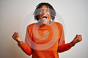 Afro american man with dreadlocks wearing orange sweater over isolated white background celebrating surprised and amazed for