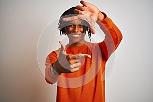 Afro american man with dreadlocks wearing orange sweater over isolated white background smiling making frame with hands and