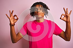 Afro american man with dreadlocks wearing t-shirt standing over isolated pink background relax and smiling with eyes closed doing