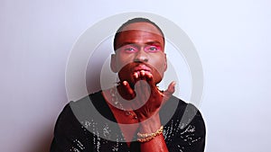afro american man in dress style with pink eyeshadow and lipstick crossdressing in fashion show studio background