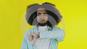 Afro-American Man Gesturing Thumbs Down on yellow Background