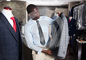 Afro-american man purchaser trying jacket in the dress shop