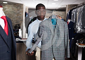 Afro-american man purchaser trying jacket in the dress shop
