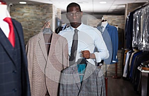 Afro-american man purchaser trying jacket in the dress shop