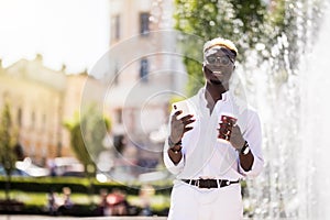 Afro american man setting playlist on smartphone the street. Young Afro American man with earphones using mobile phone and surfing