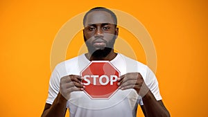 Afro-American man showing stop sign, male against racial discrimination, closeup