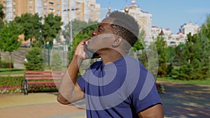 Afro-American man standing in park talking on cell phone and looks around