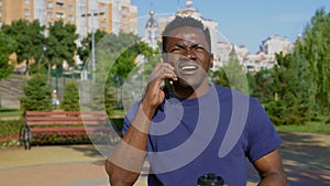 Afro-American man standing in park talking on cell phone and looks around