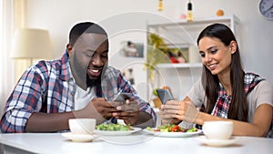 Afro-American man and woman chatting phone during lunch, lack of communication