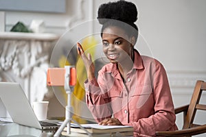 Afro-American millennial woman with afro hairstyle remote studying, working online on laptop, chatting with friends via video call