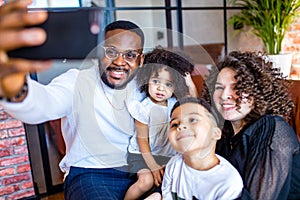 afro american mixed-raced family looking at camera selfie in cozy summer day light in living room