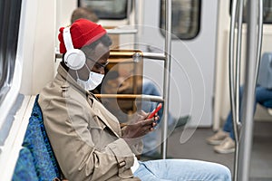 Afro-American passenger man sitting in subway train, wear face medical mask to protect yourself from flu virus, covid-19, using
