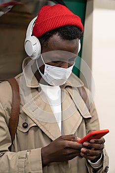 Afro-American passenger man standing in subway train, wear face medical mask to protect yourself from contact with flu virus,