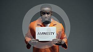 Afro-american prisoner holding Amnesty sign, asking for help, human rights