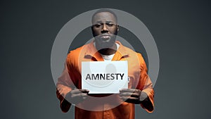 Afro-american prisoner holding amnesty sign, asking for help, human rights