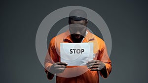 Afro-american prisoner holding stop sign, racial discrimination, persecution
