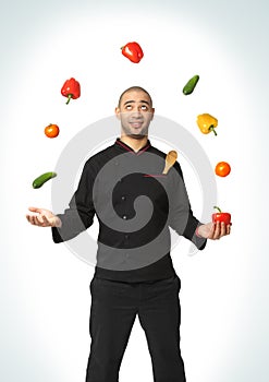 Afro American professional cook juggling vegetables.