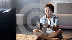 Afro-American schoolboy spending his free time playing games on console, leisure