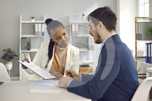 Afro american solicitor pointing at insurance contract showing client to sign