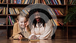 Afro-american stepmother and blonde daughter read fairy tale