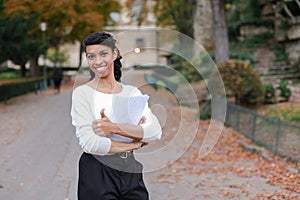 Afro american student walking with papers in autumn park, showing thumbs up.