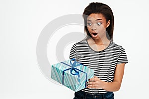 Afro american teenager girl holding and looking at present box