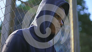 Afro-american teenager holding baseball bat, youth gang in ghetto, closeup