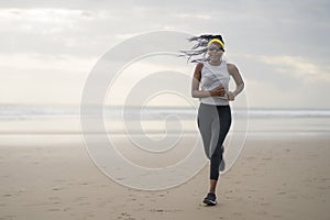 Afro American woman running on the beach - young attractive and athletic black girl training outdoors doing jogging workout at the